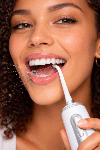 woman water flossing her teeth for good oral care 