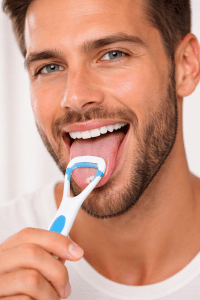 Man scraping his tongue as part of a good oral care routine 